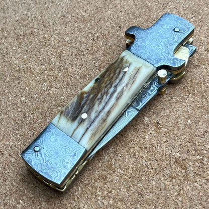Custom handmade Damascus steel folding pocket knife featuring a stag handle and sharp stainless steel blade